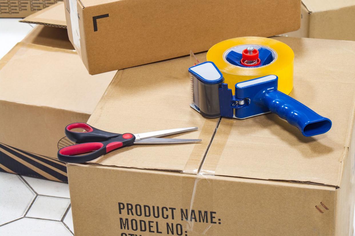 Packing tape dispenser, scissors on the cardboard box.