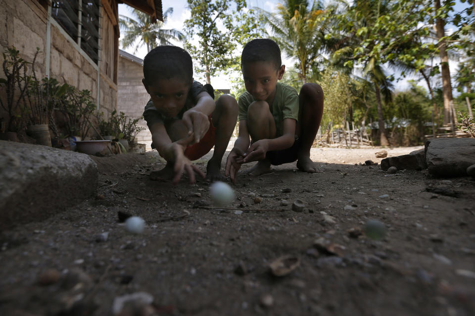 In this Oct. 22, 2018, photo, two boys play a game of marbles in Fatukoko village, West Timor, Indonesia. Children in this impoverished region of Indonesia often must walk long distances to school. Upon graduation, their job opportunities are limited, leaving them with few options beyond a lifetime of subsistence farming in a land punished by drought. (AP Photo/Tatan Syuflana)