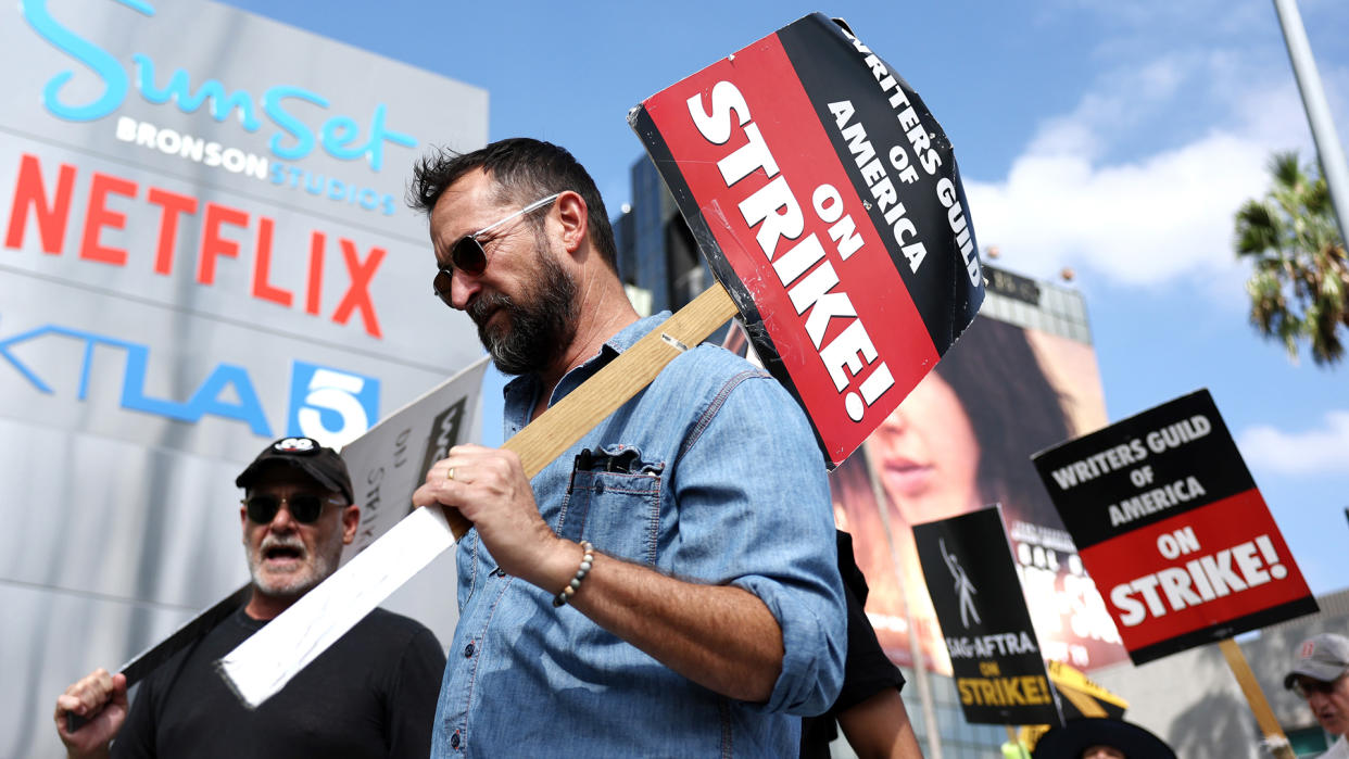  A group of writers picket outside Netflix's LA-based studio with placards and other signs. 