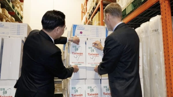 外交部長吳釗燮（左）與美國在台協會（AIT）酈英傑處長（右），共同為在捐贈美國口罩紙箱貼上「Taiwan can help」之貼紙。 (來源：外交部)            