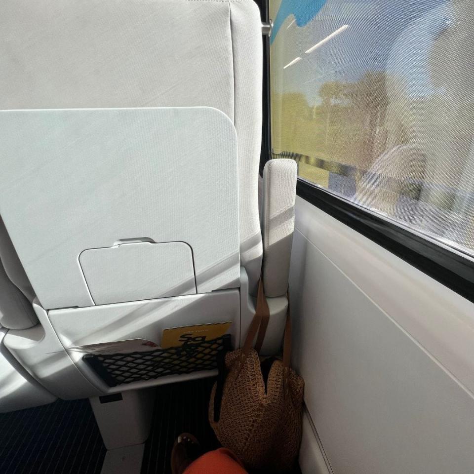 back of train seat with fold-down table next to window