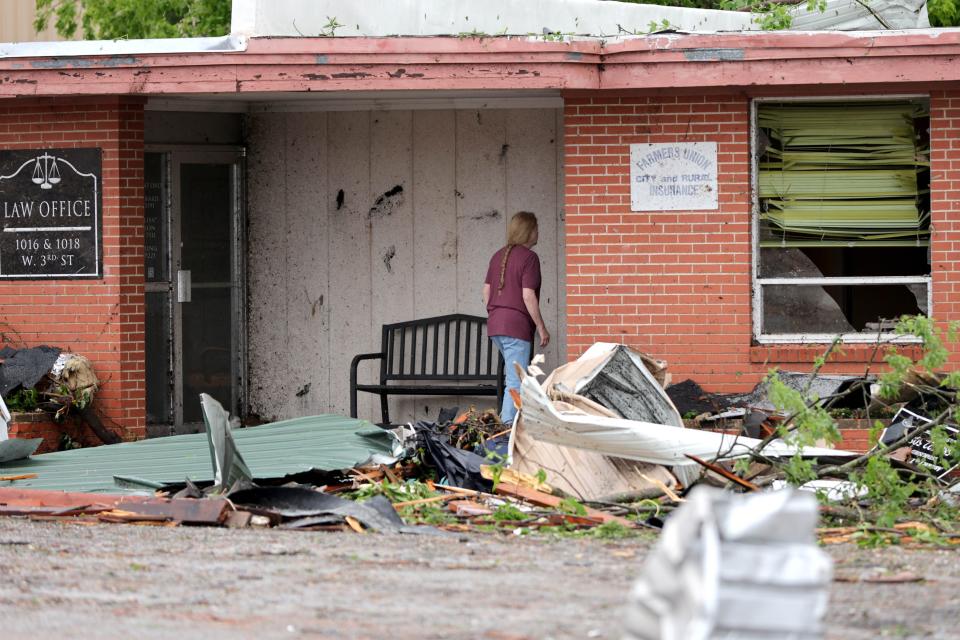 A woman looks at tornado damage to a business in Sulphur, Okla., Sunday, April 28, 2024, after severe storms hit the area the night before.