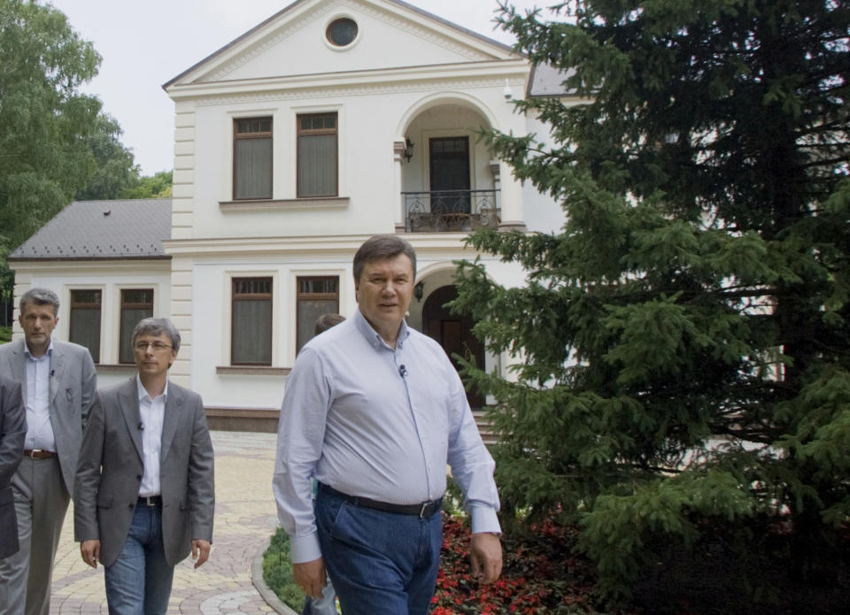 In this photo taken Friday, June 24, 2011, during a tour organized by the Ukrainian Presidential press-service, President Viktor Yanukovych, right, walks with journalists he invited to see his official residence called Mezhygirya, outside Kiev, Ukraine. When Ukraine's president opened up his home to TV cameras, he presented a cozy place with a small office just big enough for his grandchildren to play in. But his critics point to strong evidence he actually lives in very different digs: a luxurious, marble-columned mansion with a golf course, a helipad and even an ostrich enclosure. (AP Photo/Mykhailo Markiv, Presidential Press Service)