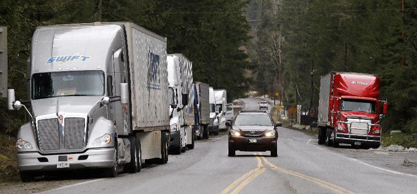 Local traffic passes trucks parked on the shoulder and waiting for eastbound Interstate 90 to open, Wednesday, Jan. 18, 2017, in North Bend, Wash. An ice storm shut down parts of major highways and interstates Wednesday in Oregon and Washington state and paralyzed the hardest hit towns along the Columbia River Gorge with up to 2 inches of ice coating the ground in some places. In Washington state, I-90, the main highway connecting western and eastern Washington, was to remain closed over Snoqualmie Pass because of hazardous winter conditions. (AP Photo/Elaine Thompson)