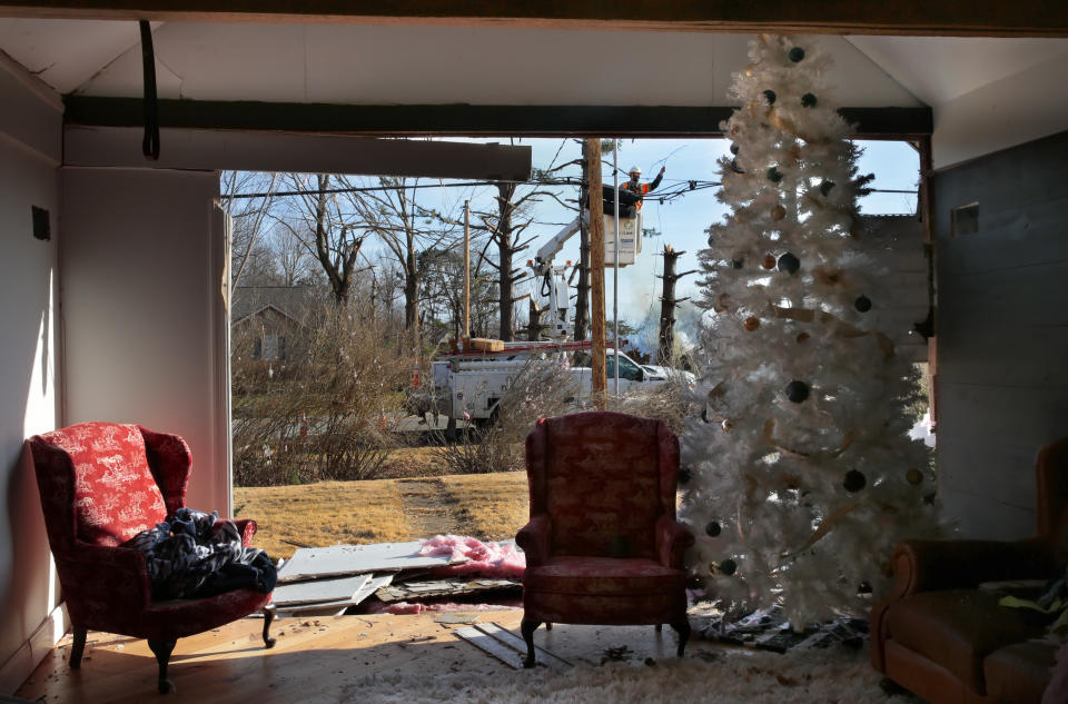 Utility crews from CenturyLink work to restore service outside a home where a Christmas tree stands in its living room at the corner of Highways F and 94 in Defiance, Mo. as cleanup continues from last Friday's tornado on Tuesday, Dec. 14, 2021. (Robert Cohen/St. Louis Post-Dispatch via AP)