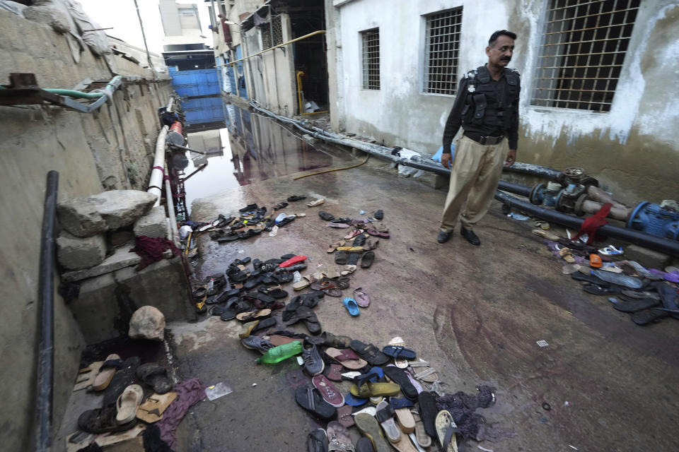 A police officer examines the site of stampede, in Karachi, Pakistan, Friday, March 31, 2023. Several people were killed in the deadly stampede at a Ramadan food distribution center outside a factory in Pakistan's southern port city of Karachi, police and rescue officials said. (AP Photo/Fareed Khan)