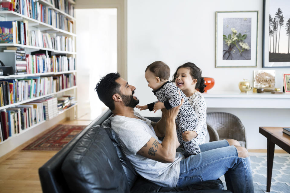 A father playing with his kids on the couch.