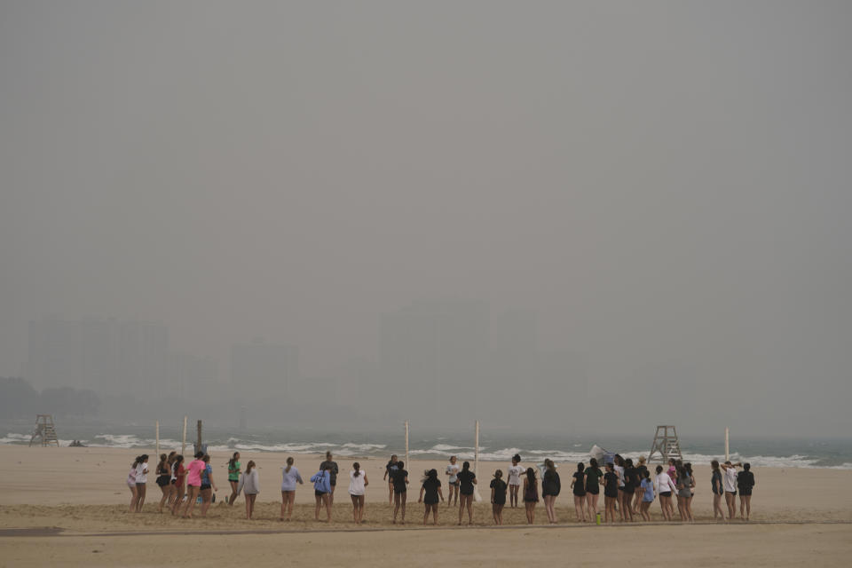 Children participate in a summer camp on Montrose Beach as buildings behind the shore are blanketed in haze from Canadian wildfires Tuesday, June 27, 2023, in Chicago. (AP Photo/Kiichiro Sato)
