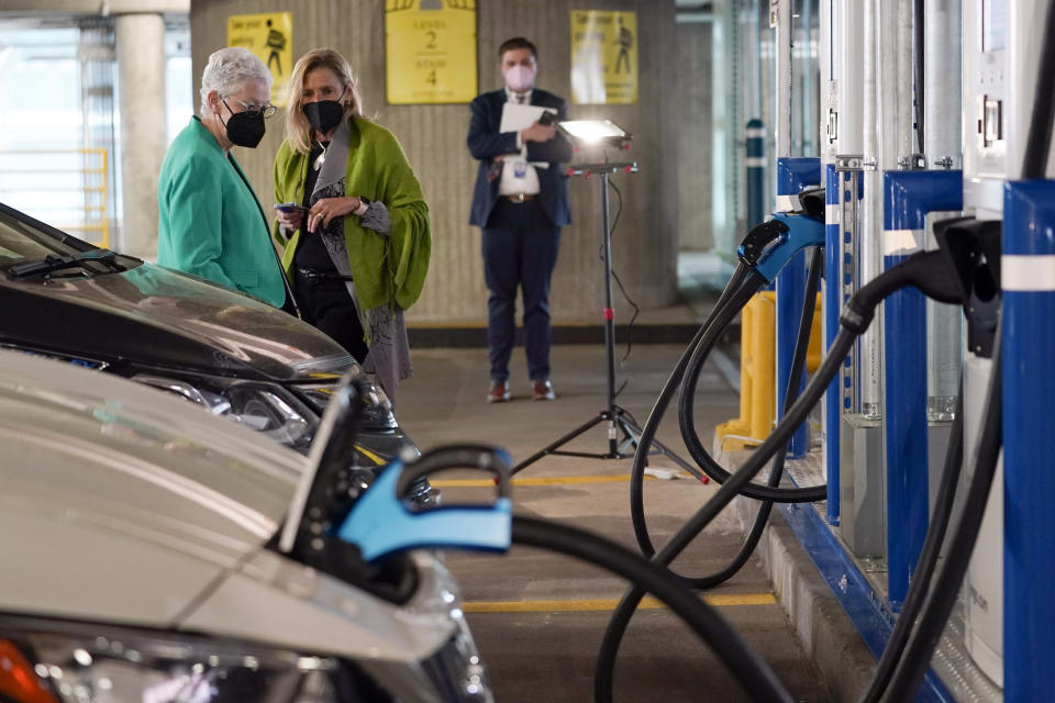 FILE - In this Thursday, April 22, 2021 file photo, White House climate adviser Gina McCarthy, left, talks with EVgo Chief Executive Officer Cathy Zoi, before the start of an event near an EVgo electric car charging station at Union Station in Washington. If the auto industry is to succeed in its bet that electric vehicles will soon dominate the roads, it will need to overcome a big reason why many people are still avoiding them: Fear of running out of juice between Point A and Point B. (AP Photo/Susan Walsh)