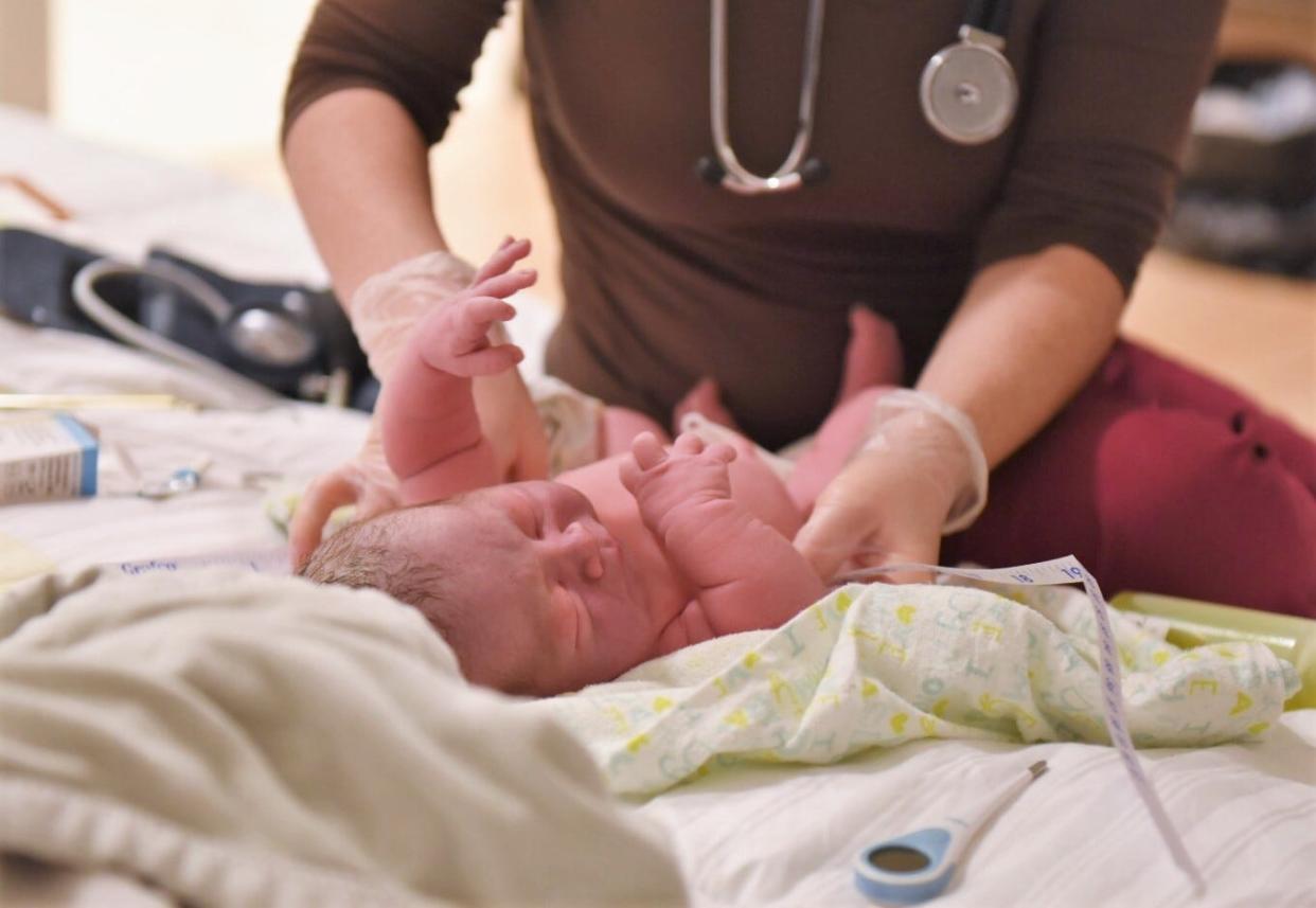 Haddie Katz, a certified professional midwife, performs a newborn exam with a client after birth.