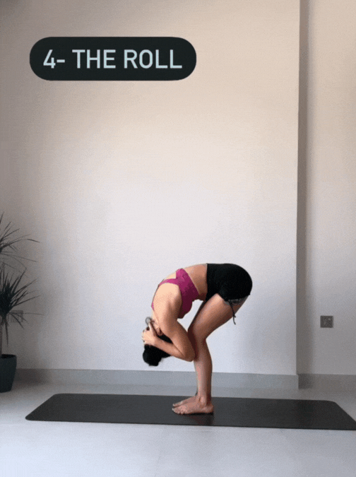 Woman standing on her yoga mat bending forward and rolling back up from Uttanasana