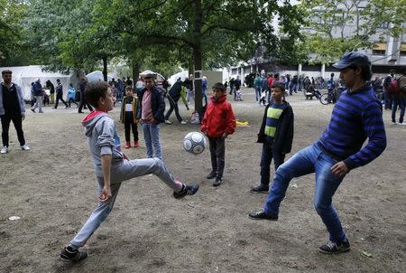 Migrants play soccer as they wait to register at a compound outside the Berlin Office of Health and Social Affairs (LaGeSo) in Berlin, Germany September 7, 2015. REUTERS/Fabrizio Bensch