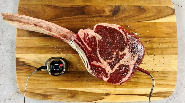 seasoned steak with probe thermometer on cutting board