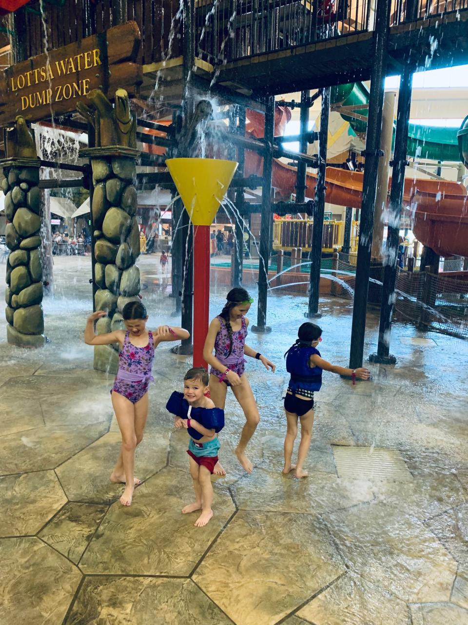 Four kids playing in a splash pad area of a water park.