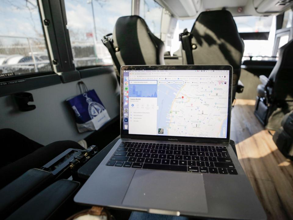 A laptop with a map of Manhattan. Bus seats and large windows are behind it.