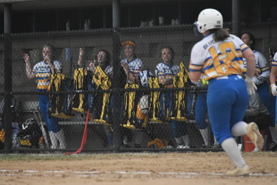 The Mitchell dugout gets on its feet as Caitlyn Mullis sprints toward first base after hitting the ball against Orleans.