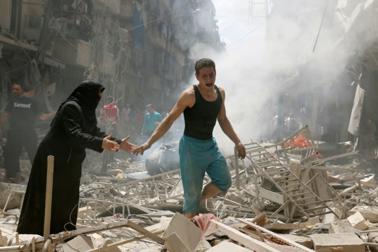 People walk amid the rubble of destroyed buildings following a reported air strike on the rebel-held neighbourhood of al-Kalasa in Aleppo, Syria on April 28, 2016