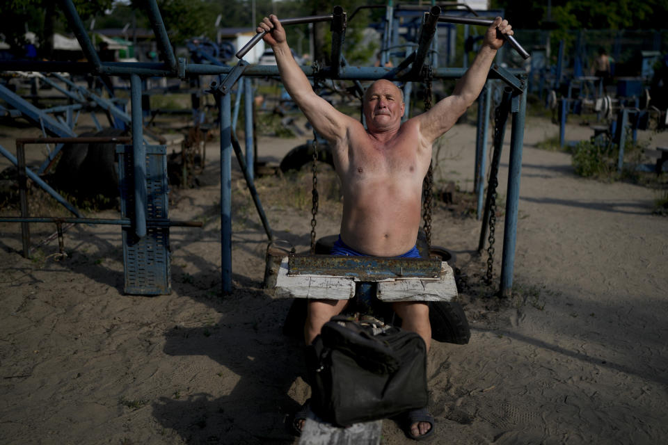 FILE - A man exercises in an outdoor gym in Kyiv, Ukraine, Thursday, June 9, 2022. With war raging on fronts to the east and south, the summer of 2022 is proving bitter for the Ukrainian capital, Kyiv. The sun shines but sadness and grim determination reign. (AP Photo/Natacha Pisarenko, File)