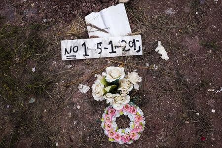 Flowers are placed on the grave of an unidentified migrant, who drowned at sea during an attempt to cross a part of the Aegean Sea from the Turkish coast, at the Saint Panteleimon cemetery of Mytilene, on the Greek island of Lesbos, October 7, 2015. Buried beneath low mounds of earth, facing Mecca, lay Afghan, Iraqi and Syrian refugees who drowned this summer in the Aegean Sea trying to reach Europe in flimsy inflatable boats. Now there is no room left in the narrow plot of land in the pauper's section of St. Panteleimon cemetery, close to where the colonnaded tombs of wealthy Greeks are built in the classical Greek style, and flowers adorn lavish marble graves. No one can say where the next bodies will be buried. Nearly half a million people, mostly Syrians, Afghans and Iraqis fleeing war and persecution, have made the dangerous journey to Europe this year. Almost 3,000 have died, the U.N. refugee agency estimates. To match story EUROPE-MIGRANTS/GREECE-DEAD Picture taken October 7, 2015. REUTERS/Dimitris Michalakis