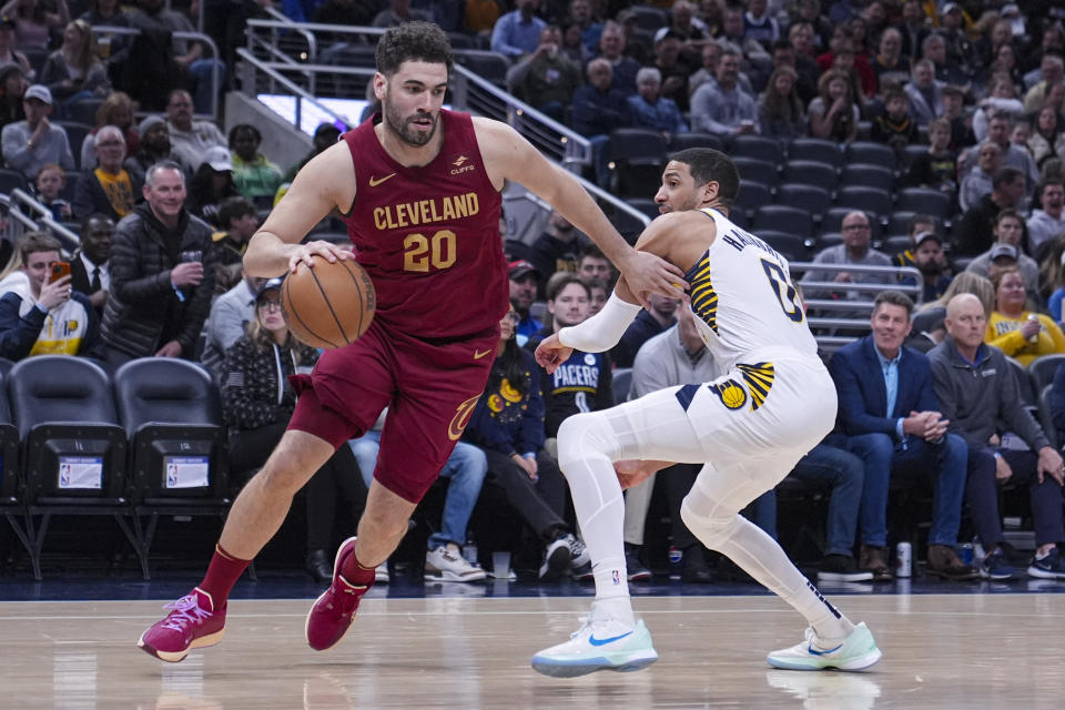 Cleveland Cavaliers forward Georges Niang (20) drives past Indiana Pacers guard Tyrese Haliburton (0) during the first half of an NBA basketball game in Indianapolis, Monday, March 18, 2024. (AP Photo/Michael Conroy)