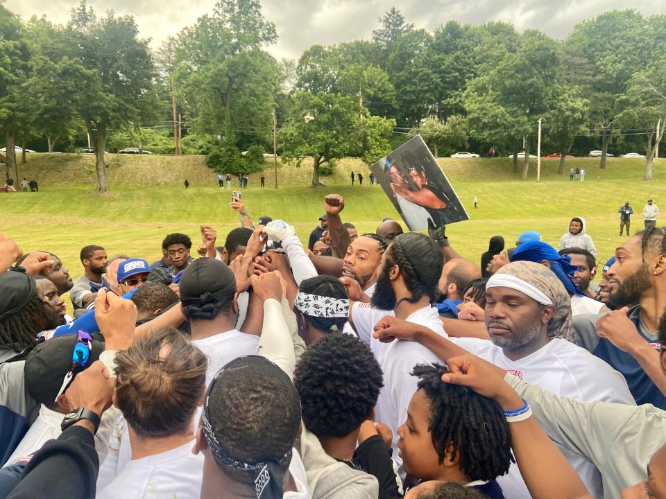 Poughkeepsie High School graduates huddle and join hands following an alumni football game last Saturday.