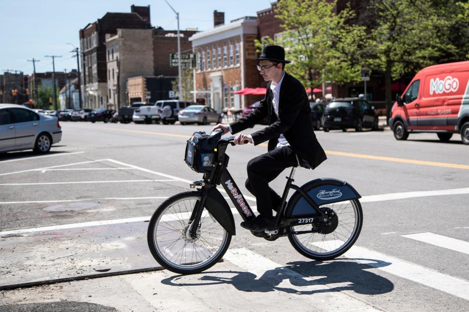 Mendel Pinson, 18, rides a MoGo bike across Selden Street at Second Avenue in Detroit on May 13, 2022. Pinson is a student at the Yeshivas Lubavitch Zekelman campus He has been using the MoGo bike every Friday, the past four years, to reach out to people in the community celebrating Sabbath, the Jewish day of rest.