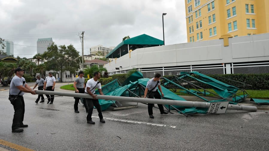 Members of the Tampa Fire Rescue Dept., remove a street pole after large awnings from an apartment building blew off from winds associated with Hurricane Idalia Wednesday, Aug. 30, 2023, in Tampa, Fla. Idalia made landfall earlier this morning along the Big Bend of the state. (AP Photo/Chris O’Meara)