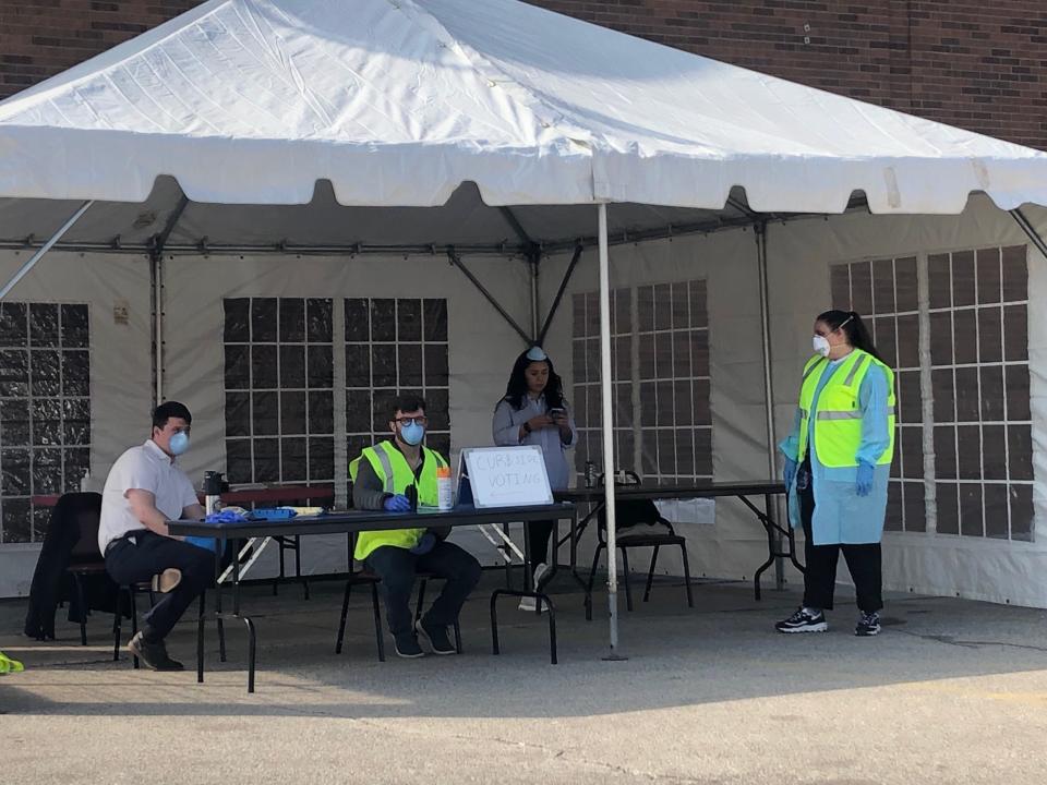 Poll workers stand ready to assist voters with curbside voting, but few voters came through at South Division High School on April 7 in Milwaukee. Poll worker Natisia Martinez says 15-20 cars used the curbside voting area since polls opened at 7 a.m. Poll workers wore masks and gowns.