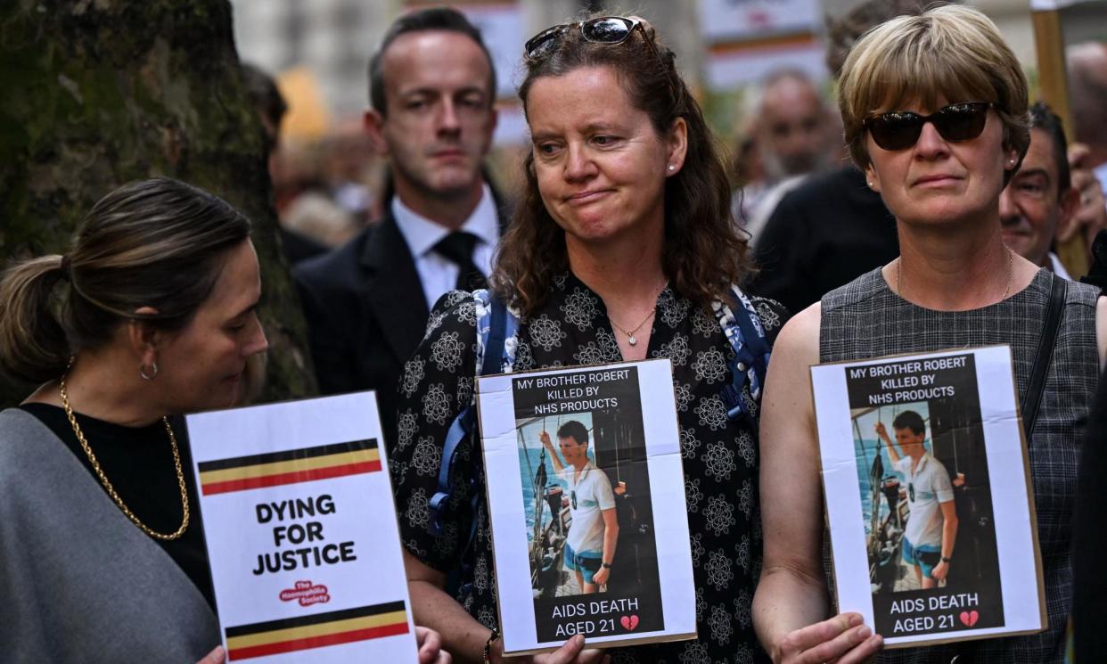 <span>Demonstrators hold placards showing a victim of the NHS infected blood scandal at a march in July 2023.</span><span>Photograph: Justin Tallis/AFP/Getty Images</span>