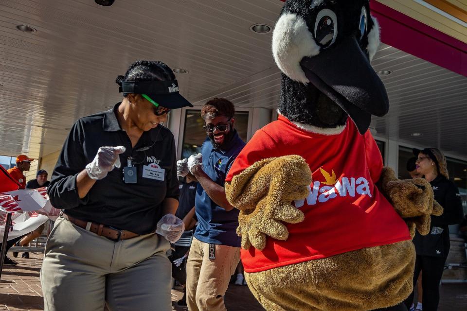 Rosalind "Ms. Ros" McKinnes, West Palm Beach, left, Sheldon Guy, Coral Springs, center and costumed Wawa mascot Wally dance as Wawa personnel celebrated a grand opening with a new store location at 45th Street and Interstate 95 in West Palm Beach, Fla., on February 9, 2023. 