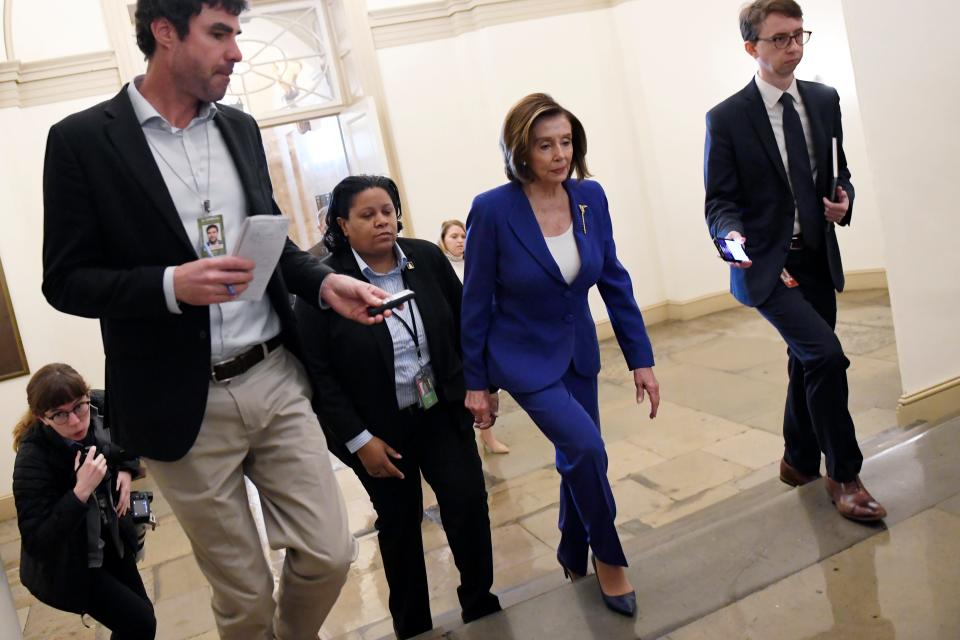 House Speaker Nancy Pelosi, D-Calif., is followed by reporters and staff as she arrives on Capitol Hill on  March 27, 2020.