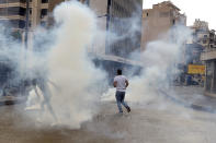 Protesters runs from the smoke of tear gas during a protest against French President Macron's comments over Prophet Muhammad caricatures, near the Pine Palace, which is the residence of the French ambassador, in Beirut, Lebanon, Friday, Oct. 30, 2020. A few hundred demonstrators held a protest called for by a Sunni Islamist party, Hizb ul-Tahrir, against French cartoons of the Prophet Muhammad. (AP Photo/Bilal Hussein)