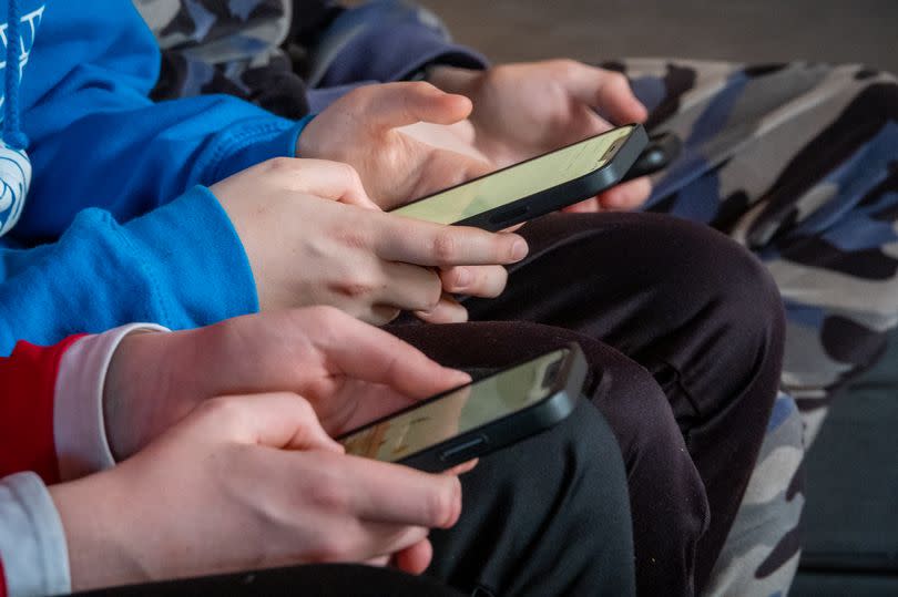 A line of hands playing with phones