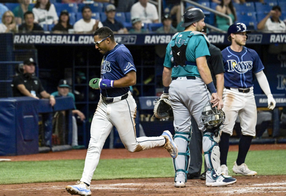 Tampa Bay Rays outfielder Richie Palacios, left, runs past Seattle Mariners catcher Cal Raleigh, center, and Rays' Taylor Walls, right, to score on a wild pitch during the fourth inning of a baseball game Monday, June 24, 2024, in St. Petersburg, Fla. (AP Photo/Steve Nesius)