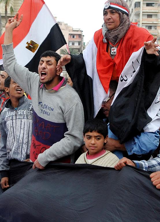 Egyptian supporters of the military-installed government wave national flags and shout slogans in Alexandria on January 25, 2014