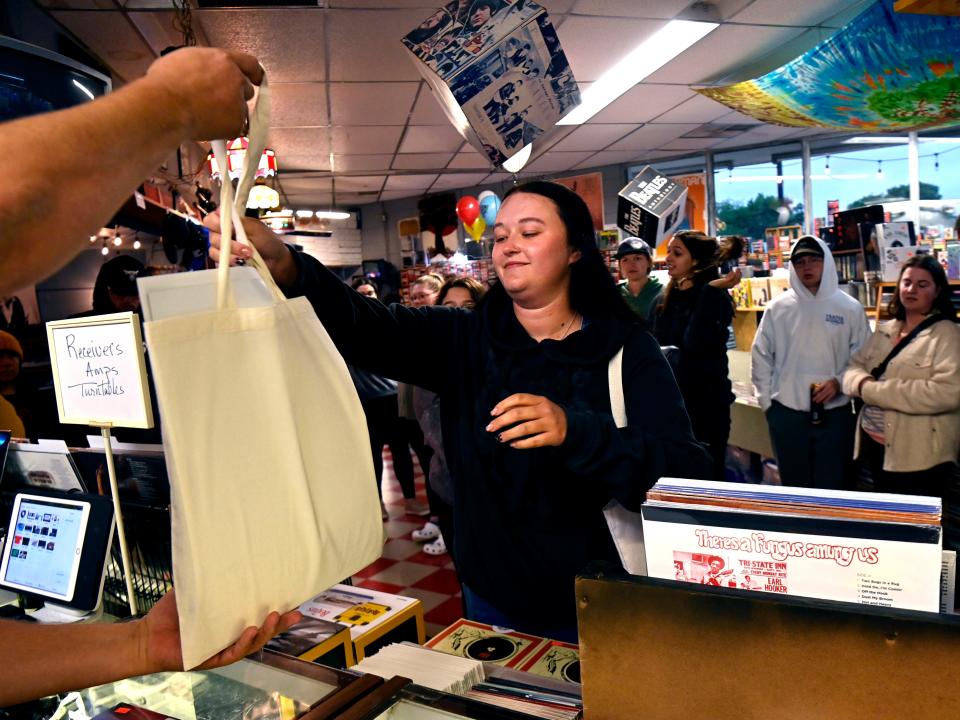 Kassidy Holland receives her purchases from Jon Howell on Record Story Day Saturday. Holland was first on the list, signing up the day before and only able to leave the parking lot to visit the nearby Mezamiz coffee shop.