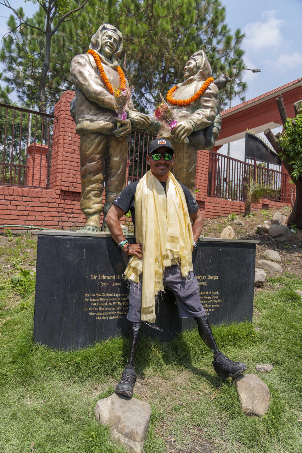 Hari Budha Magar, former Gurkha veteran and double amputee climber who scaled Mount Everest poses for a photo in front of the statues of New Zealander Edmund Hillary, left, and his Sherpa guide Tenzing Norgay on the 70 anniversary of the first ascent of Mount Everest in Kathmandu, Nepal, Monday, May 29, 2023. The 8,849-meter (29,032-foot) mountain peak was first scaled by Hillary and Norgay on May 29, 1953. (AP Photo/Niranjan Shrestha)