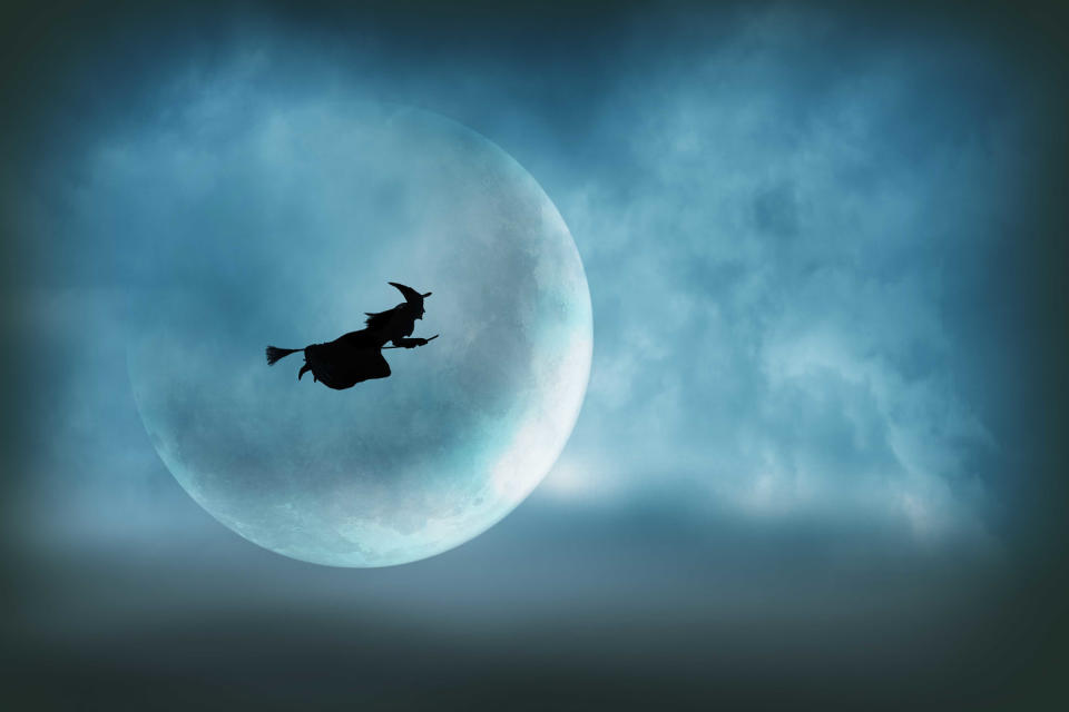 Flying Halloween Witch Silhouetted In Front of Large Moon (Getty Images)