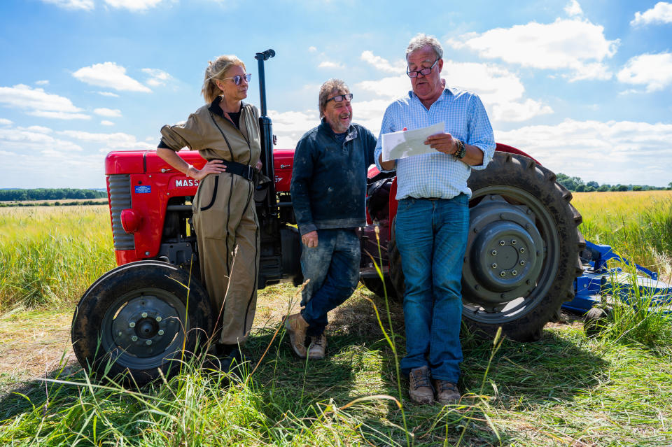 Lisa Hogan and Jeremy Clarkson stood in front of a red tractor in a field.