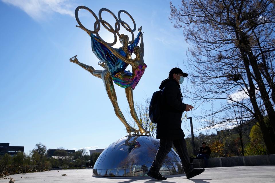 A visitor to the Shougang Park walks past the a sculpture for the Beijing Winter Olympics in Beijing, China, Tuesday, Nov. 9, 2021. China on Monday, Dec. 6, 2021, threatened to take "firm countermeasures" if the U.S. proceeds with a diplomatic boycott of February's Beijing Winter Olympic Games. (AP Photo/Ng Han Guan)