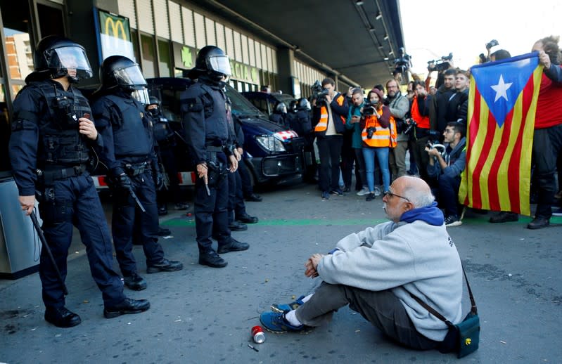 Un hombre sentado en el suelo frente a agentes de la policía antidisturbios mientras los manifestantes independentistas catalanes asisten a una manifestación frente a la estación de tren de Barcelona Sants, España, el 16 de noviembre de 2019