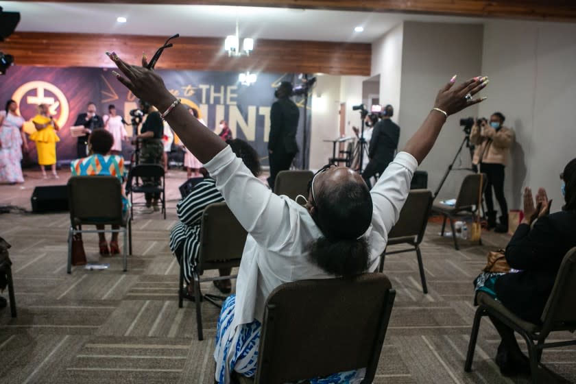 LOS ANGELES, CA - APRIL 04: A church member with hands raised worships during Easter Sunday service at New Mount Calvary Missionary Baptist Church amidst the pandemic on Sunday, April 4, 2021 in Los Angeles, CA. (Jason Armond / Los Angeles Times)