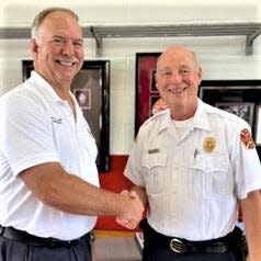 New Fire Chief Matthew McBirney, left, and former Chief David Barnes shake hands.