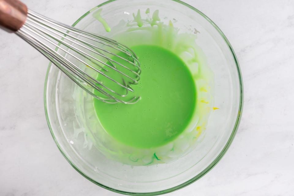 Whisk in glass bowl of lime-green icing