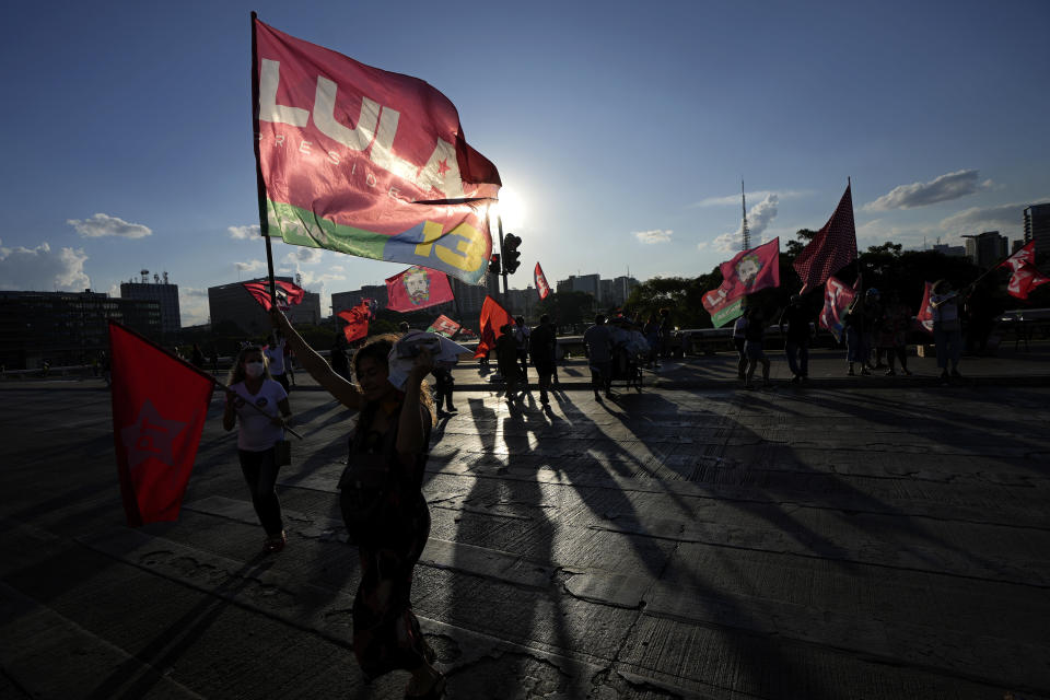 Supporters carry flags with the name of Brazil's former president Luiz Inacio Lula da Silva, who is running for president again, during a campaign event at a bus station in Brasilia, Brazil, Tuesday, Oct. 25, 2022. Lula is facing President Jair Bolsonaro in a presidential run-off election set for Oct. 30. (AP Photo/Eraldo Peres)