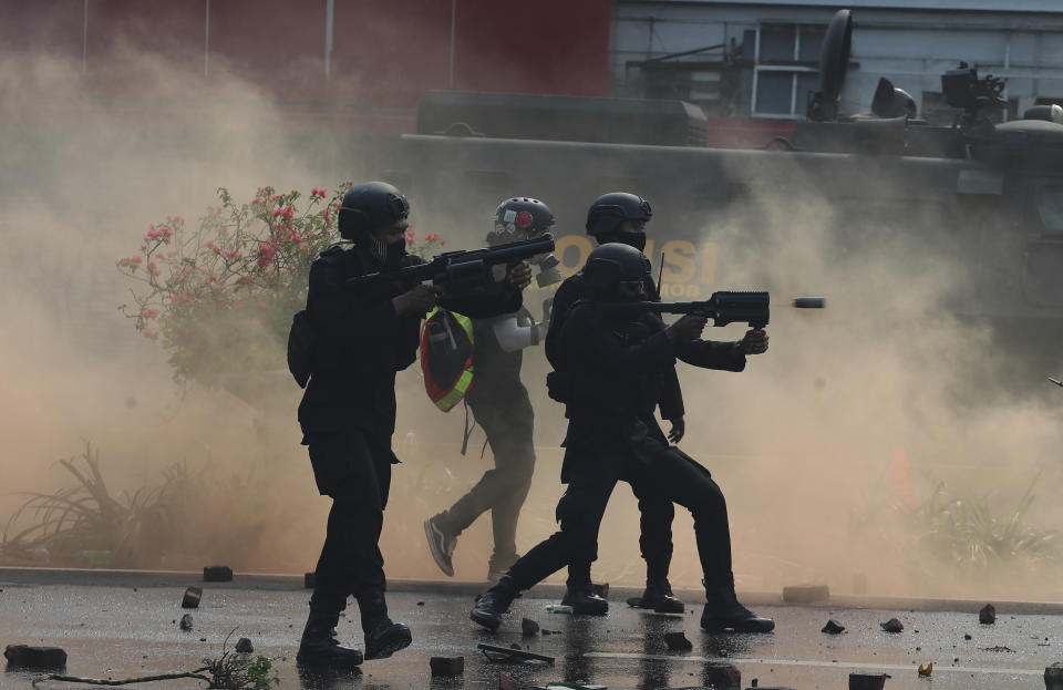 Police fire tear gas towards advancing protesters during a rally in Jakarta, Indonesia, Thursday, Oct. 8, 2020. Thousands of enraged students and workers staged rallies across Indonesia on Thursday in opposition to a new law they say will cripple labor rights and harm the environment. (AP Photo/Achmad Ibrahim)