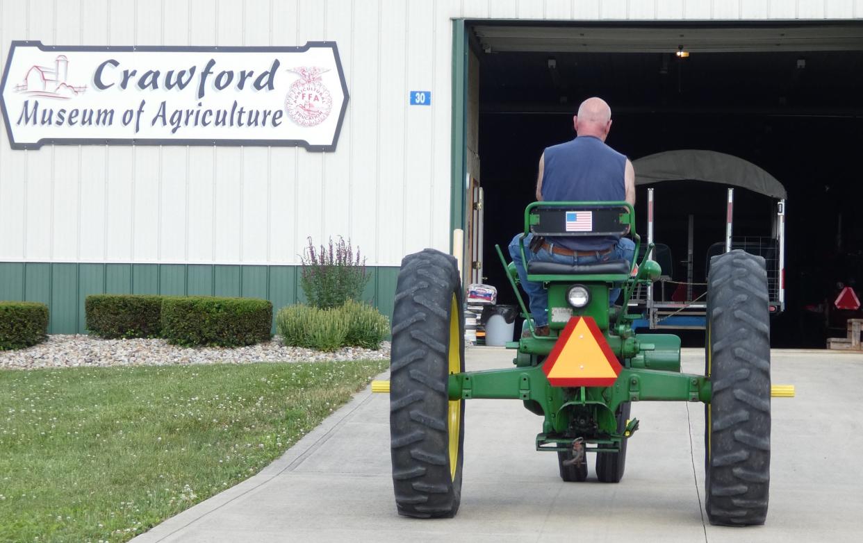 Roger Haas rides his 1951 John Deere B tractor toward the Crawford Museum of Agriculture at the Crawford County Fairgrounds on Monday. The tractor will be on display during Crawford Antique Farm Machinery's 22nd annual show, which runs Thursday through Saturday.