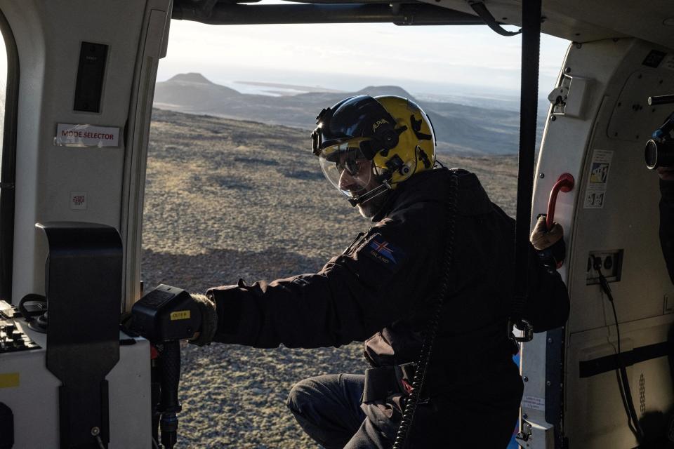 A member of the Coast Guard flies in a helicopter near the evacuated town of Grindavik, in Iceland (REUTERS)