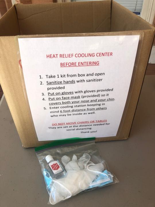 A box offering coronavirus protection supplies like hand sanitizer, gloves and a mask are offered at the Salvation Army Phoenix downtown headquarters where a heat relief station was set up on Thursday, May 28, 2020, in Phoenix, Ariz. The heat relief station offering cold water and a cool place inside to rest out of the brutal sun will be open every day through Sunday while an excessive heat warning is in effect. (AP Photo/Anita Snow)