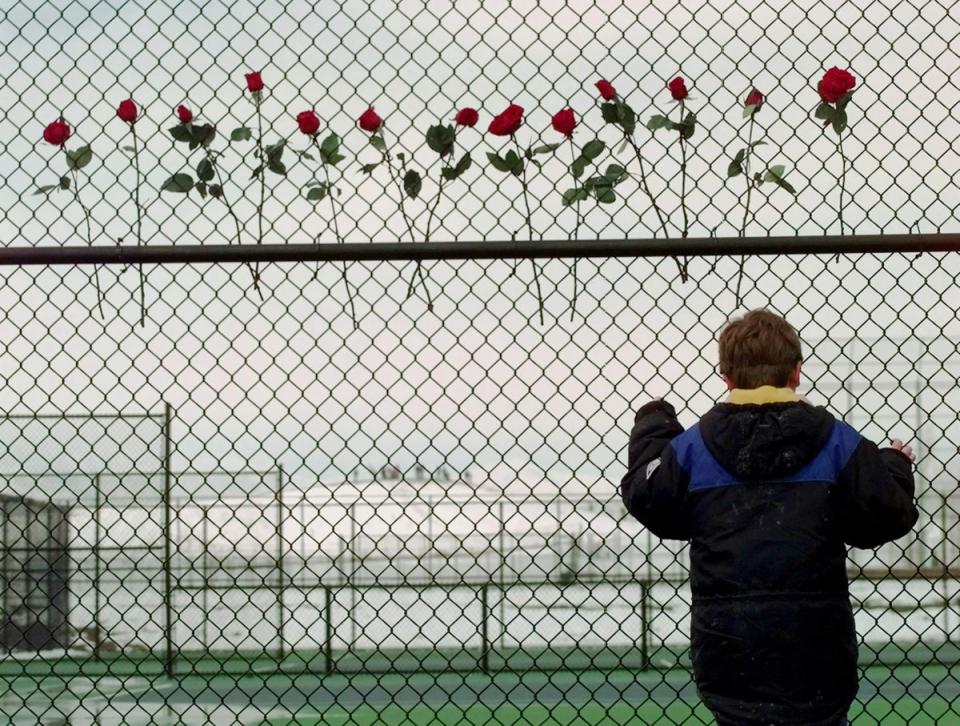 A boy looks through the fence at the Columbine High School tennis courts four days after the attack by two student shooters that killed 12 teens and one teacher, injuring 24 more (AP1999)